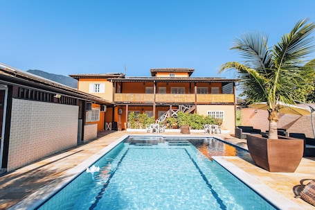 Una piscina al aire libre, sombrillas, sillones reclinables de piscina