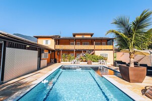 Una piscina al aire libre, sombrillas, sillones reclinables de piscina