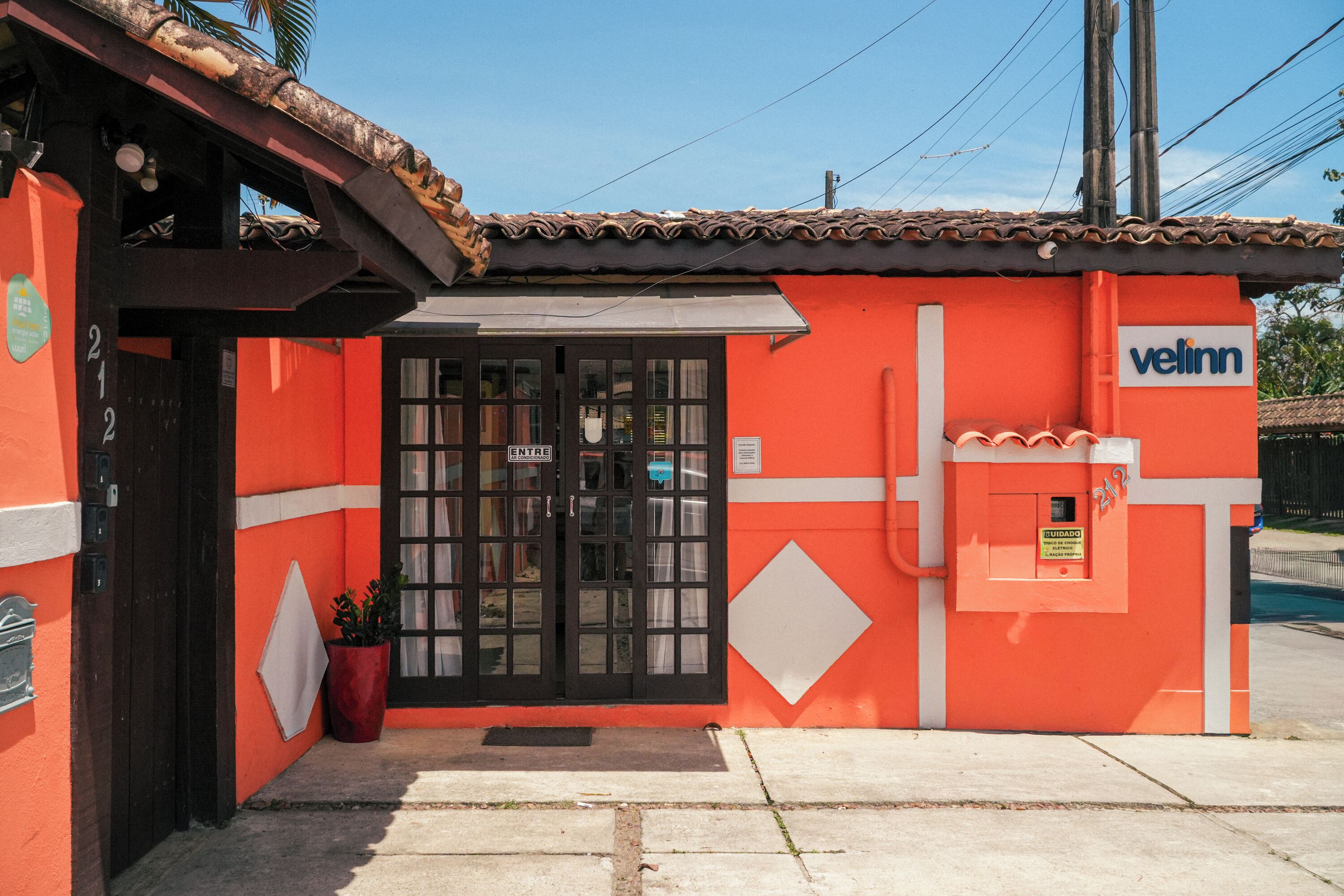 A building with a red exterior, a black door, and a sign that reads "ENTRE".