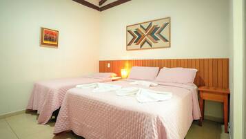 A hotel room with two beds, a wooden headboard, a wall-mounted artwork, and a bedside table with a lamp.