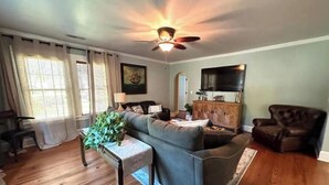 Ein Wohnzimmer mit einer Couch, einem Couchtisch, einem Fernseher und einem Deckenventilator.