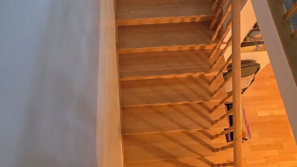 A wooden staircase with a curved arch at the top, leading to a lower level.