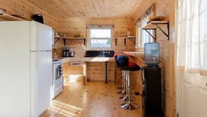 A compact wooden cabin with a kitchenette, a bar stool, and a large window. - Steps to Lake on the Mountain, 10Minutes to Picton (Prince Edward)