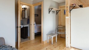 A room with a wooden floor, a bed, a desk, and a chair. There is a door leading to another room. - Steps to Lake on the Mountain, 10Minutes to Picton (Prince Edward)