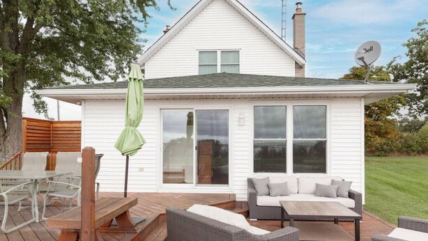 A white house with a deck, outdoor furniture, and a satellite dish.
