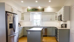 A modern kitchen with white cabinets, stainless steel appliances, and a central island.