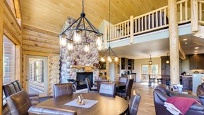 A spacious dining area with a stone fireplace, leather seating, and a high ceiling with exposed beams. - Alma Mountain Getaway w/ Private Hot Tub & Views (Alma)