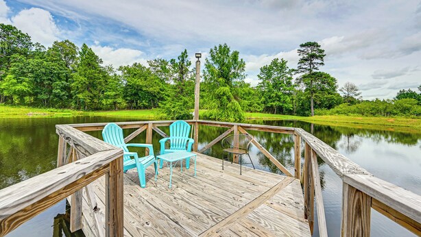 A wooden dock with chairs and a lamp post overlooking a calm lake surrounded by lush greenery. - Fishing Pond & Pier: Secluded Broken Bow Cottage! (Broken Bow)
