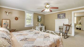 A bedroom with a bed, a desk, a rocking chair, and wall decorations including animal skulls and a painting.