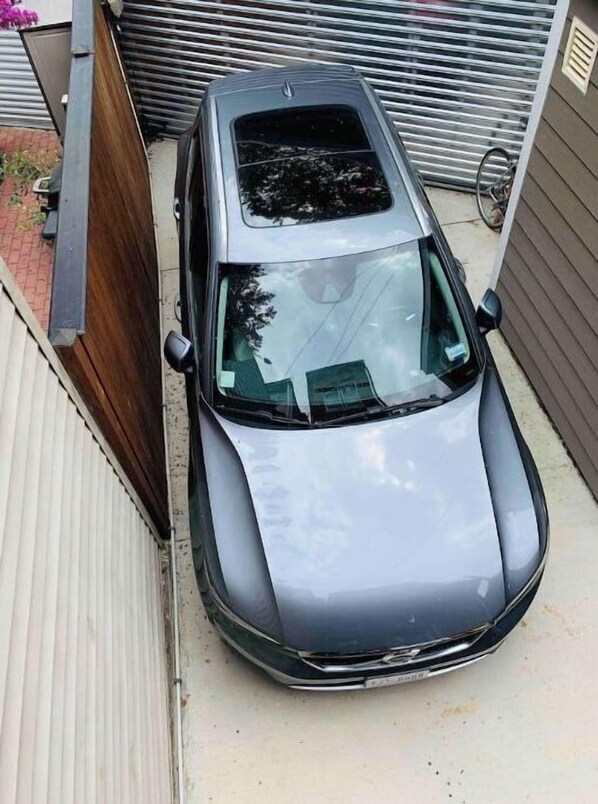 A silver car parked in a narrow driveway.