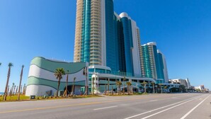 A modern hotel with a curved facade and multiple high-rise buildings in the background.