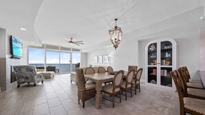 A spacious living area with a dining table, sofas, and a bookshelf.