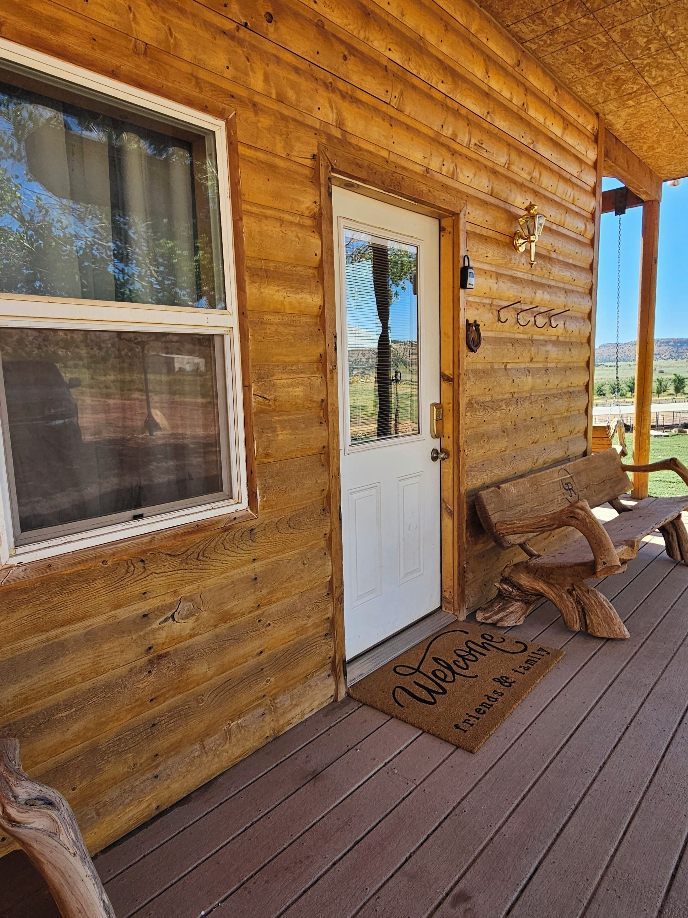 A wooden cabin with a white door, a bench, and a doormat.