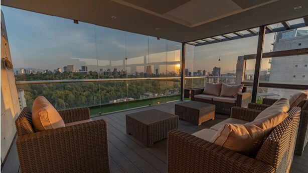 Een modern balkon met buitenmeubilair van riet en uitzicht op de stad.