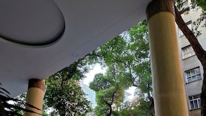 A covered outdoor area with columns, a metal fence, and a parked car. - Lapinha 40 graus (Rio de Janeiro)