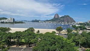 A coastal cityscape with a prominent mountain, numerous boats in the harbor, and a mix of urban and natural landscapes. - Lapinha 40 graus (Rio de Janeiro)