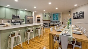 Une cuisine moderne dotée d’un îlot central, de tabourets de bar et d’un coin repas aménagé pour prendre un repas.