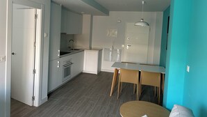 A modern kitchen with white cabinets, a built-in oven, and a sink. There is a dining area with a table and chairs. - Perfect, Modern Studio In The Heart Of Alicante (Alicante (Alacant))