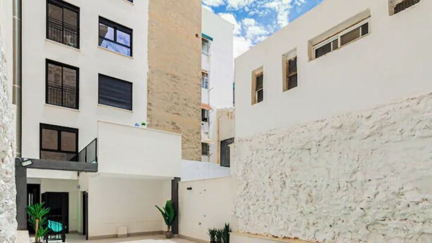 A modern building with a swimming pool, a stone wall, and a clear blue sky. - Perfect, Modern Studio In The Heart Of Alicante (Alicante (Alacant))