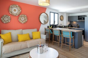 A modern living room with a sofa, a dining area with chairs, a kitchen with appliances, and a large mirror on the wall. - Apartment sea view Orient bay beach (Saint-Martin)