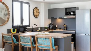 A modern kitchen with a central island, bar stools, a microwave, a coffee maker, and a refrigerator. - Apartment sea view Orient bay beach (Saint-Martin)