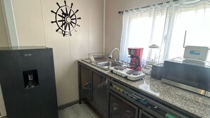 Une cuisine compacte équipée d’un réfrigérateur, d’un évier, d’une cuisinière et d’une machine à café.