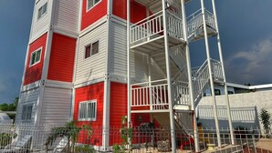 Un immeuble à plusieurs étages aux couleurs rouge et blanche, doté de balcons et d’un escalier.
