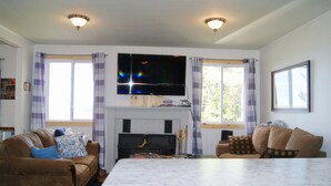 A living room with a flat-screen TV, a fireplace, two sofas, and a large marble table.