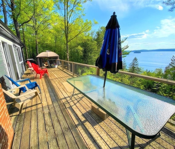 Eine Terrasse mit einem Glastisch, Stühlen und einem Sonnenschirm.