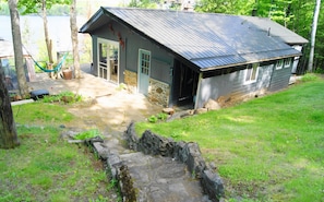 Eine rustikale Holzhütte mit Metallbedachung, Stein Fundament und einer Holzdiele Terrasse.