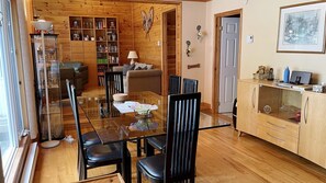 Un espace repas avec une table en verre, des chaises noires et un plancher en bois.