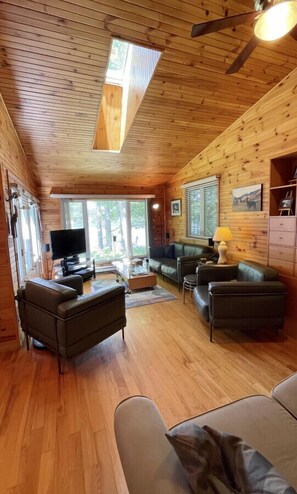 A wooden interior with a sofa, television, and a ceiling fan.