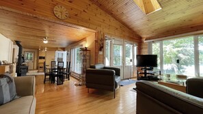 A spacious wooden interior with a living area, dining space, and a kitchen. - Great Value! Lasswade Lake Cottage Rental (North Kawartha)