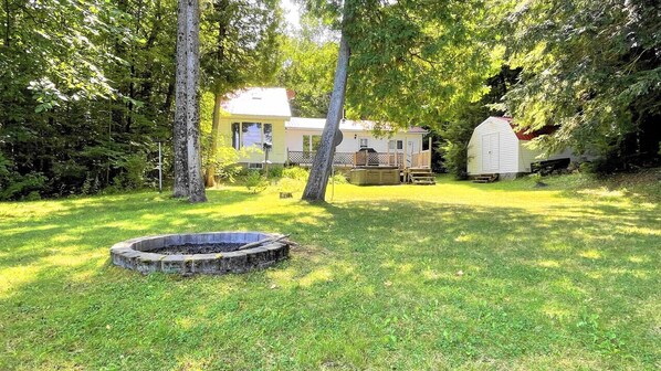 A house with a fenced yard, a wooden deck, and a small shed.