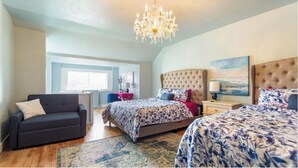 A spacious bedroom with a large bed, a smaller bed, a sofa, a chandelier, and a painting on the wall. - McKinley Mansion Half Building, sleeps 35, Gym, Arcade Room (Pocatello)