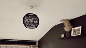 Ein Schlafzimmer mit zwei Betten, einer Steinwand, einem Fenster mit Aussicht, einer Hängelampe und einem Regal mit Bildern.
