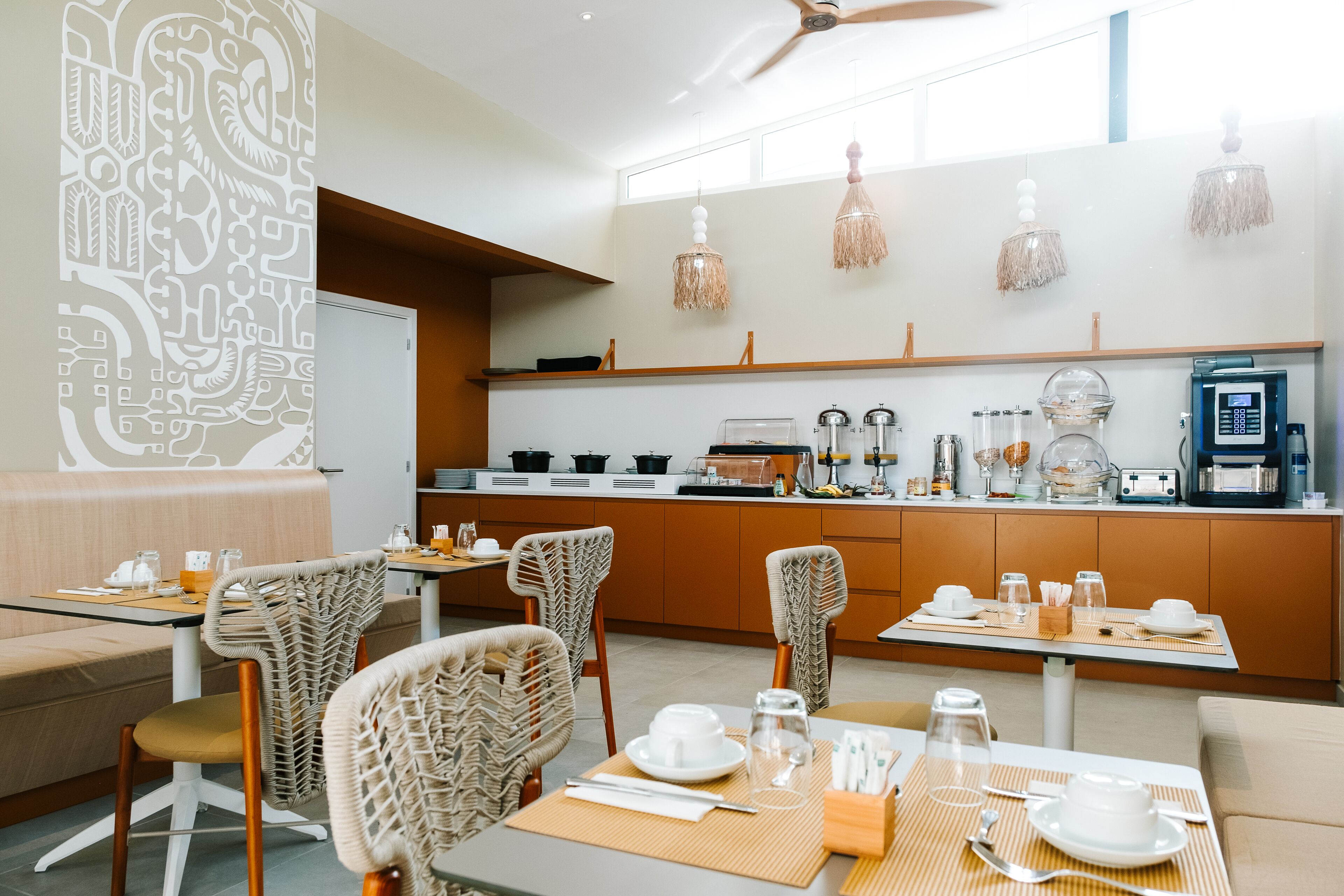 A modern dining area with wicker chairs, a buffet setup, and a coffee machine.