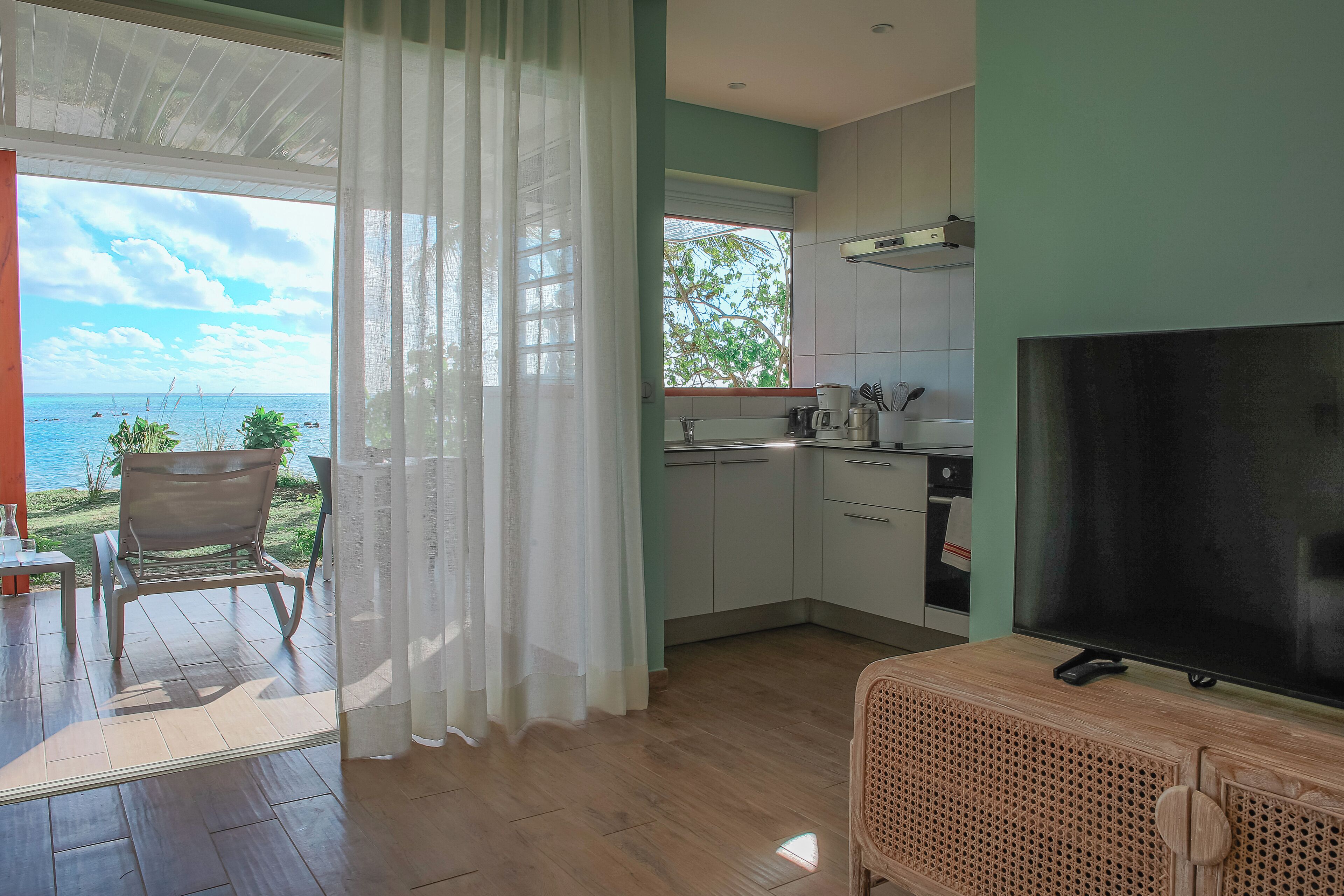 Cocina moderna con televisor, comedor y vista al mar.