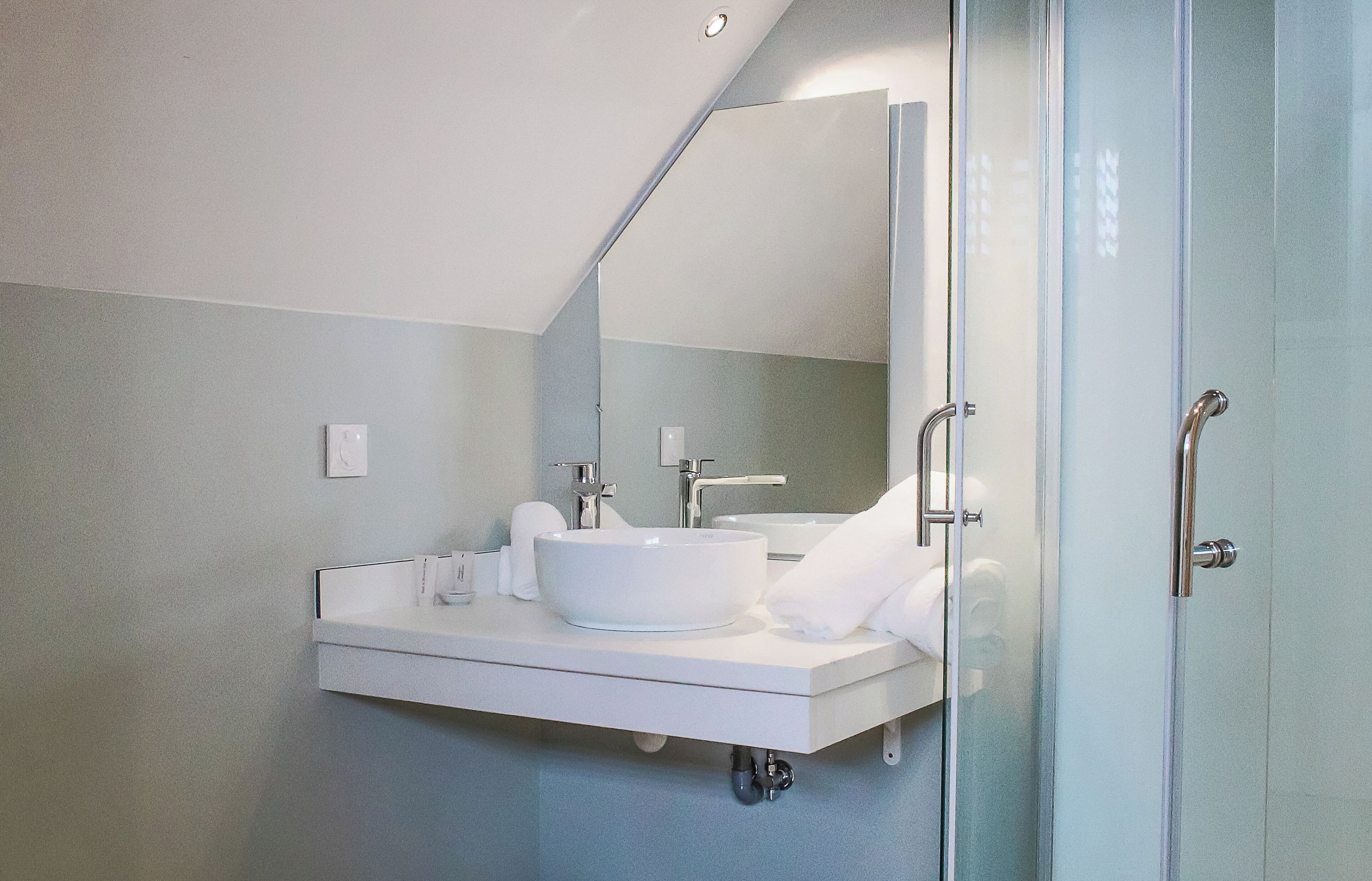 Een moderne badkamer met een witte wastafel, spiegel en handdoekhouder.