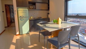 A modern kitchen with a refrigerator, microwave, and dining area with chairs and a table.