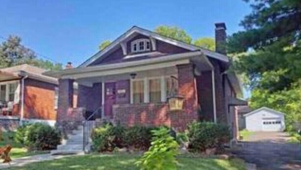 A two-story house with a front porch, a garage, and a well-maintained lawn. - Unique Family home (St. Louis)