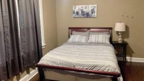 A bedroom with a bed, a nightstand, a lamp, and a painting on the wall. - Unique Family home (St. Louis)