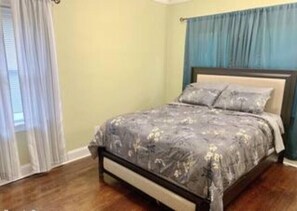 Une chambre à coucher avec un lit, des rideaux et un plancher en bois.