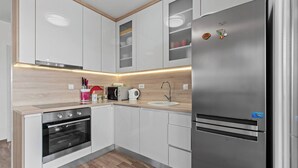 Una cocina moderna con armarios blancos, un refrigerador de acero inoxidable, horno empotrado y encimera de madera.