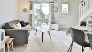 Una sala de estar moderna con un sofá gris, una mesa redonda y un comedor con mesa y sillas.