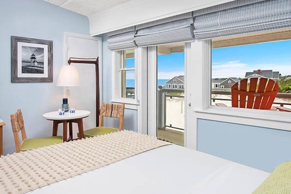 Relax in bed while watching waves through wide sunny windows.