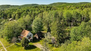 Una casa rural rodeada de un bosque frondoso, con un cielo despejado.