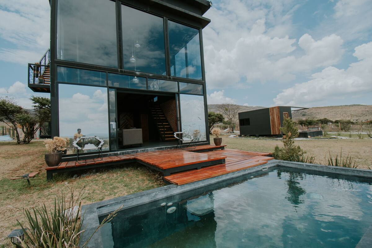 Une maison moderne avec une façade en verre, une terrasse en bois et une piscine.