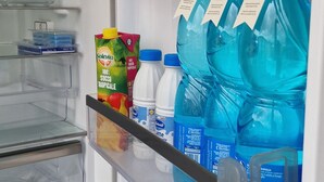 A refrigerator with shelves containing bottled water and a carton of juice.