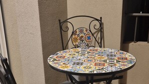 A round table with a colorful tile pattern, a chair with a cushion, and a metal frame.